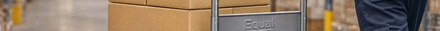 Warehouse worker pushing an Equal blue platform trolley loaded with cardboard boxes in a storage facility